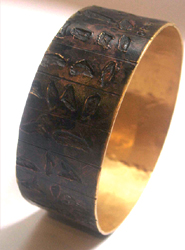 Un brazalete del autor, en bronce y chapado en oro. 